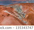 Vivid orange and red hills with white and green mineral deposits, a wooden staircase, and a dramatic pink and purple sky in Iceland's geothermal area. 135343747