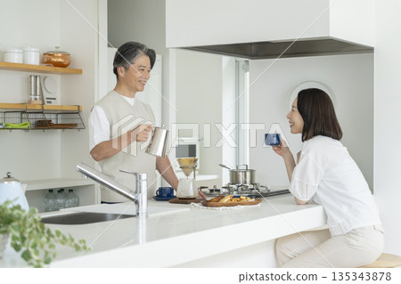 A couple in their 50s enjoying coffee in the kitchen 135343878