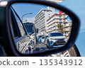行駛中的汽車側視鏡映照出城市交通擁擠和城市景觀。 135343912