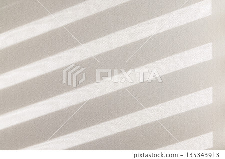 牆面背景由透過窗戶的柔和陽光和百葉窗的陰影構成。 135343913