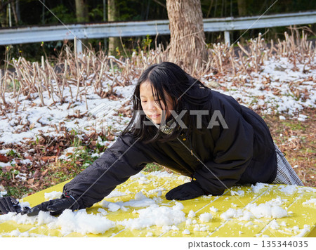 A girl child having fun playing a snowball fight in a snowy park on a winter morning 135344035