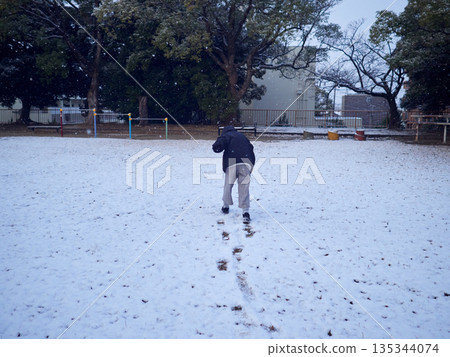 A child playing in the snow in a park in winter 135344074