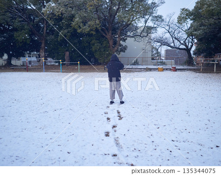 A child playing in the snow in a park in winter 135344075
