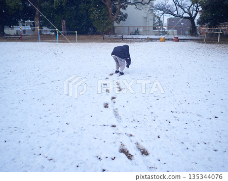 A child playing in the snow in a park in winter 135344076