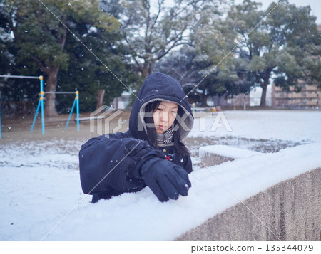 A female junior high school student playing in the snow in a park in winter 135344079