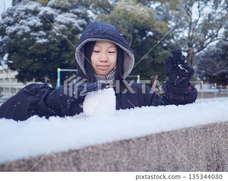 A female junior high school student playing in the snow in a park in winter 135344080