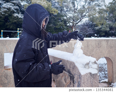 A child playing in the snow in a park in winter A child playing in the snow in a park in winter 135344081