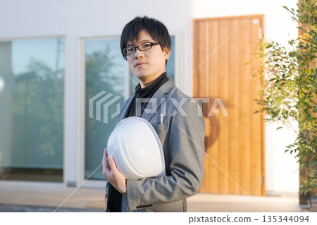 一個戴著頭盔的男人站在一棟房子前。 一個戴著頭盔的男人站在一棟房子前。 135344094