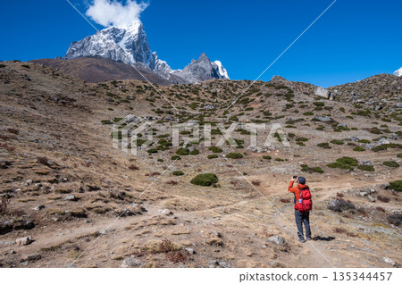 Tourist take a photograph of snowcapped mountains on the way to Dingboche village, Nepal. 135344457