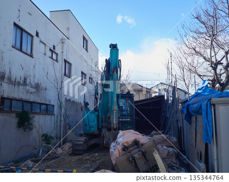 Heavy machinery demolishing a house in a residential area of a city in winter and garbage 135344764
