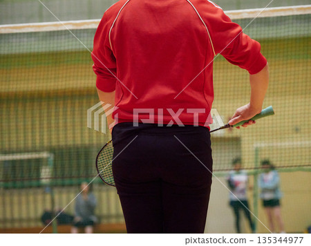 A woman practicing badminton in a gym A woman practicing badminton in a gym 135344977