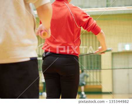 A woman practicing badminton in a gym 135344982