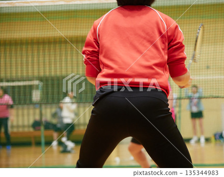 A woman practicing badminton in a gym A woman practicing badminton in a gym 135344983