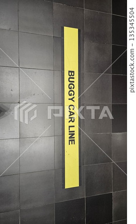 A bold yellow strip marked BUGGY CAR LINE stands out on tiled flooring, guiding pedestrian flow with clear signage 135345504