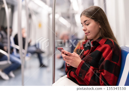 girl sitting in subway car with phone girl sitting in subway car with phone 135345530
