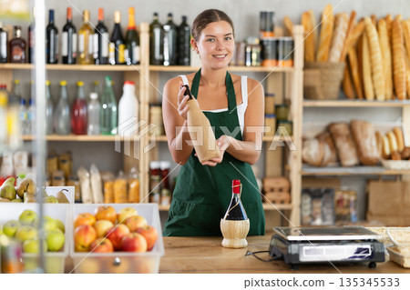 Female salesperson offers to buy bottle of wine in liquor department of grocery supermarket 135345533