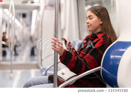 Girl sit in tram car with smartphone, getting to work 135345580