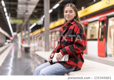 Woman sitting on a bench at a subway station Woman sitting on a bench at a subway station 135345601