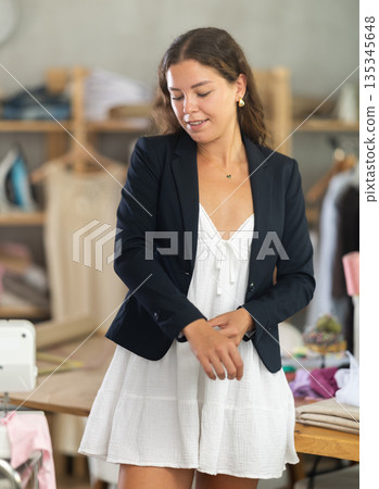 Woman trying on a jacket in the workshop 135345648