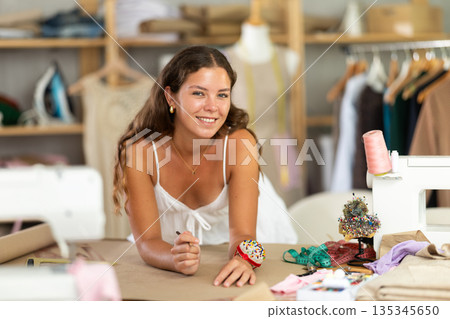 Female dressmaker sketching clothing pattern in workshop Female dressmaker sketching clothing pattern in workshop 135345650