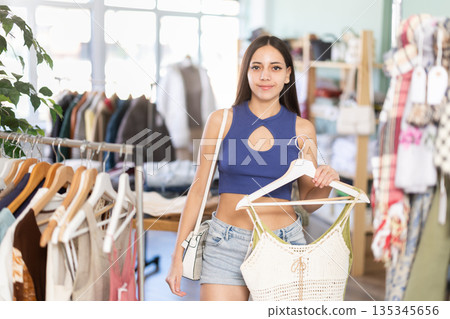 Young woman choosing top in clothing store 135345656