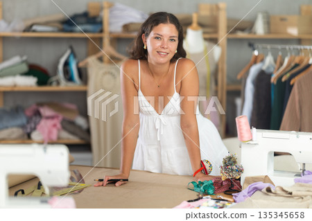 young dressmaker draws a sketch with the help of curved rulers 135345658