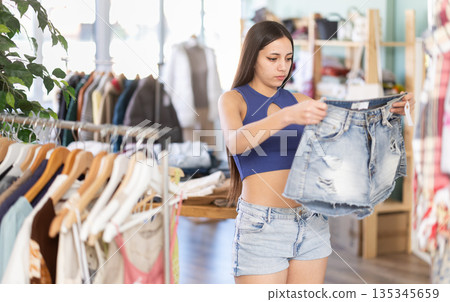 Young woman choosing shorts in clothing store Young woman choosing shorts in clothing store 135345659