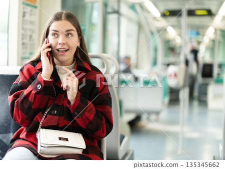 Girl sit in tram car and emotionally talks on phone, getting to work Girl sit in tram car and emotionally talks on phone, getting to work 135345662
