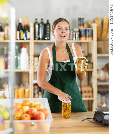Young woman seller offering olives in grocery store Young woman seller offering olives in grocery store 135345678