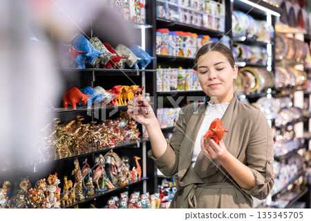 Happy woman tourist buys traditional spanish souvenirs - mosaic bull figurines 135345705