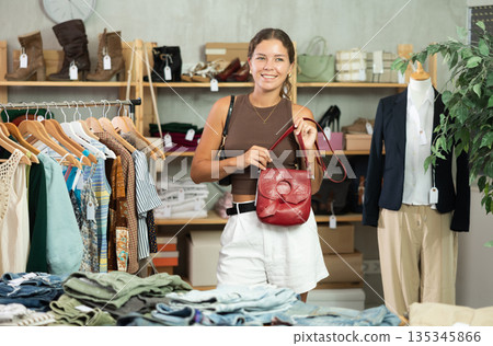 Girl customer choose handbag in store, and buyer carefully examines product. Girl customer choose handbag in store, and buyer carefully examines product. 135345866
