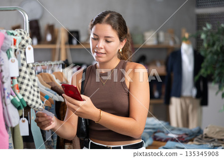 Woman squinting on mobile scarf in store Woman squinting on mobile scarf in store 135345908