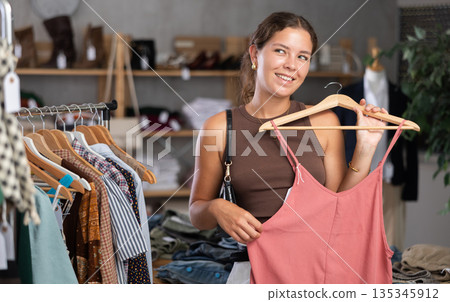 Young woman choosing a dress in a clothing store Young woman choosing a dress in a clothing store 135345912