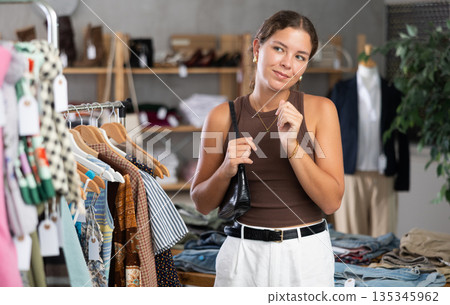 Girl is intently examining sales area of womens clothing store and looking for something 135345962