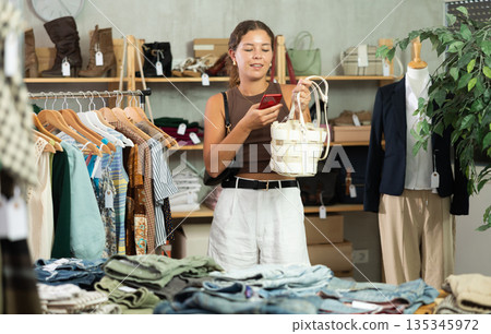 Woman scanning her handbag on her mobile Woman scanning her handbag on her mobile 135345972