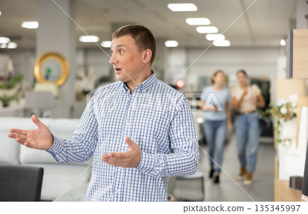 Mans eyes scan room furniture store, searching for perfect item to complete living space Mans eyes scan room furniture store, searching for perfect item to complete living space 135345997