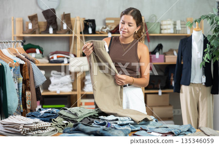 Woman standing near shelves with pants in a store 135346059