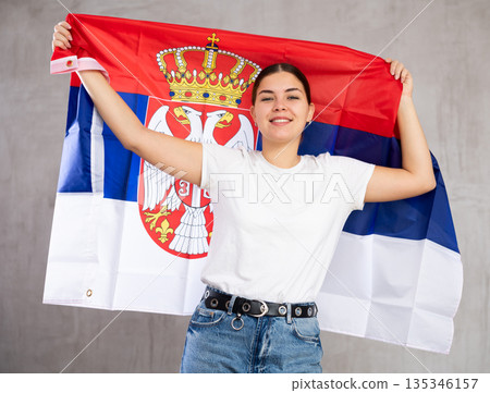Happy girl stands with flag of Serbia. Isolated on gray background Happy girl stands with flag of Serbia. Isolated on gray background 135346157