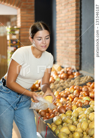 Young female shopper selects and buys potatoes in supermarket 135346187