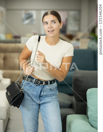 Interested young girl choosing furniture for home in shop 135346204