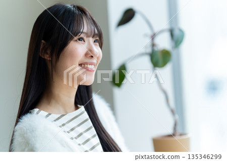 一位微笑、神態放鬆的女子正望著窗外。 135346299