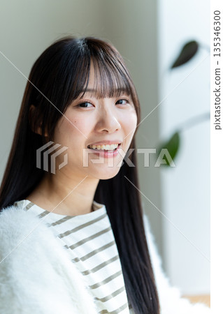 一位微笑、神態放鬆的女子正望著窗外。 135346300