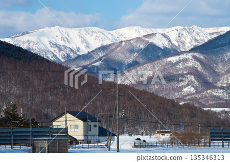 Snowy scenery of a rural village with houses and snow fences 135346313