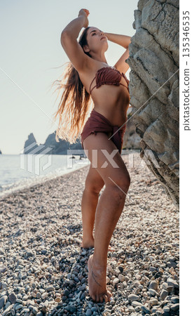 Woman in a Bikini Posing on a Pebble Beach 135346535