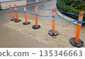 Weathered plastic safety posts with blue rope attachment on wet pavement 135346663