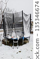 Calm winter scene featuring snowcovered trampoline and surrounding fence 135346674