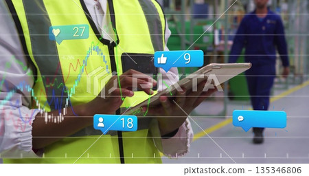 Tapping tablet screen, supervisor in neon vest reading factory floor line graphs and social icons Tapping tablet screen, supervisor in neon vest reading factory floor line graphs and social icons 135346806