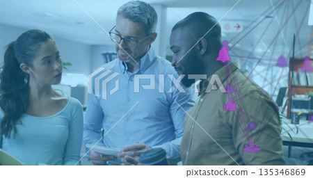 Standing team in dress shirts studying network overlay on glass partition in office, with notebook Standing team in dress shirts studying network overlay on glass partition in office, with notebook 135346869