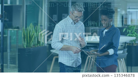 Discussing digital data two professionals pointing at tablet screen at open office, with folder 135346878