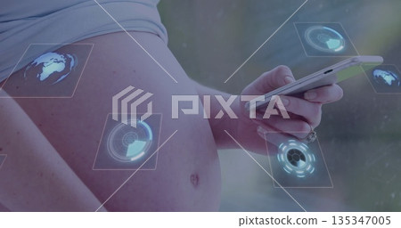 Displaying pregnant torso holding smartphone in softly lit interior, with holographic UI elements Displaying pregnant torso holding smartphone in softly lit interior, with holographic UI elements 135347005